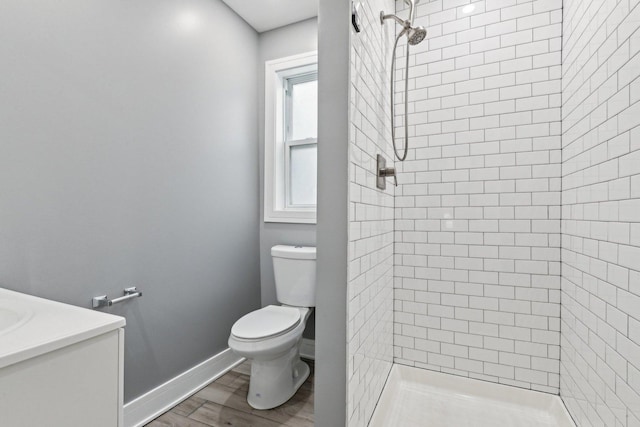 bathroom with toilet, wood finished floors, a shower stall, baseboards, and vanity