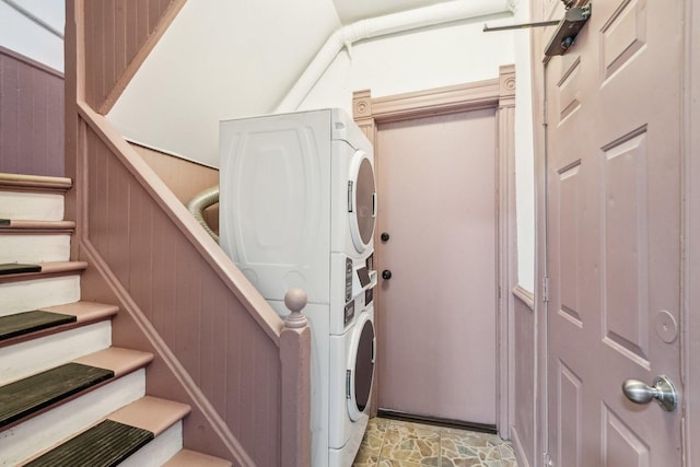 laundry room with wooden walls, laundry area, and stacked washer / dryer