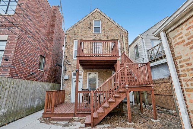 back of house with stairway, brick siding, a wooden deck, and fence