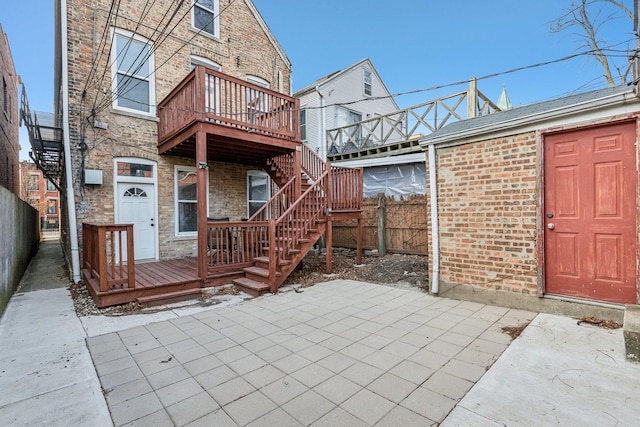 back of house featuring stairway, a patio, brick siding, and fence