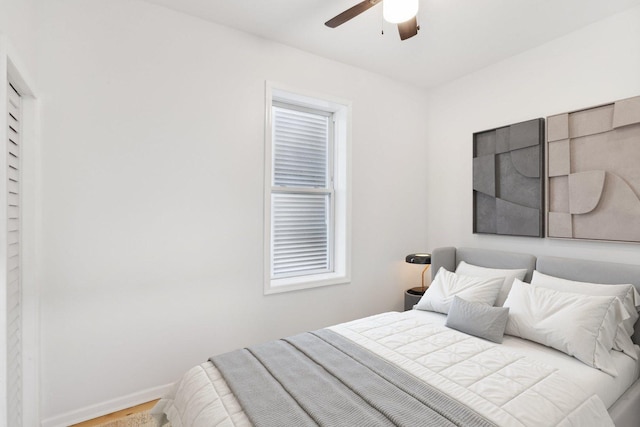 bedroom with a ceiling fan, baseboards, and wood finished floors