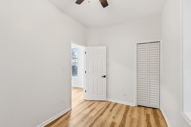 unfurnished bedroom featuring baseboards, light wood-style flooring, and a ceiling fan