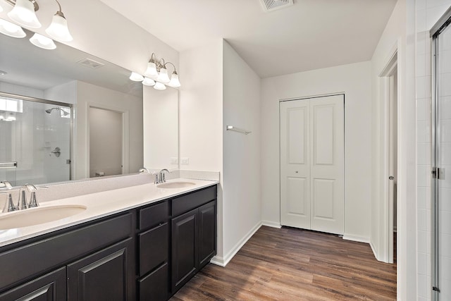 full bath featuring a sink, double vanity, wood finished floors, and a shower stall