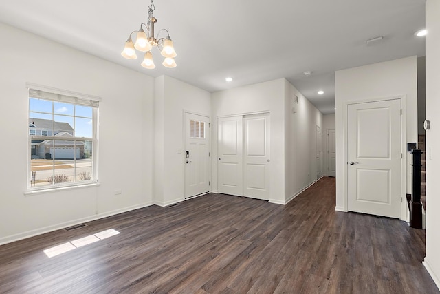 empty room featuring visible vents, a notable chandelier, dark wood finished floors, recessed lighting, and baseboards