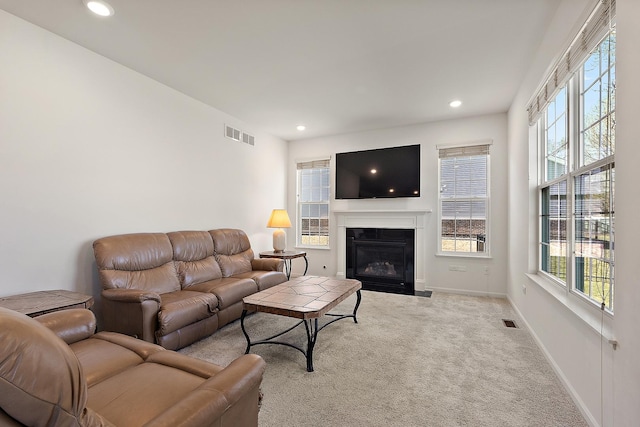 carpeted living room with recessed lighting, a fireplace with flush hearth, baseboards, and visible vents