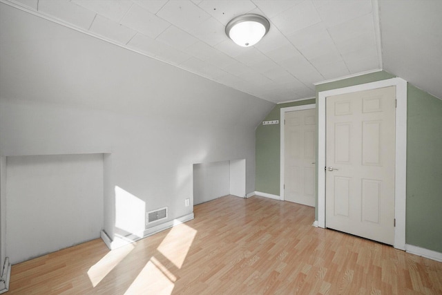 bonus room featuring visible vents, baseboards, light wood-style flooring, and vaulted ceiling