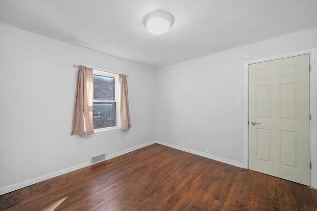 spare room featuring wood finished floors, visible vents, and baseboards