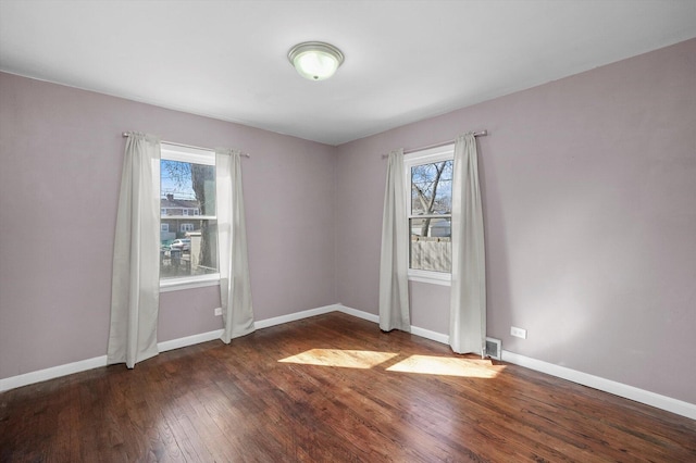 empty room with visible vents, baseboards, and hardwood / wood-style floors