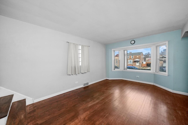 unfurnished room featuring baseboards, visible vents, and wood-type flooring