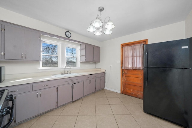 kitchen featuring range with gas stovetop, gray cabinets, freestanding refrigerator, and a sink