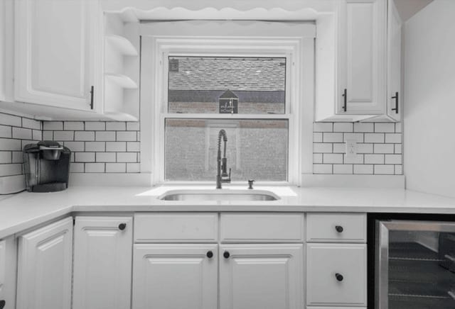 kitchen featuring a sink, wine cooler, white cabinets, and light countertops