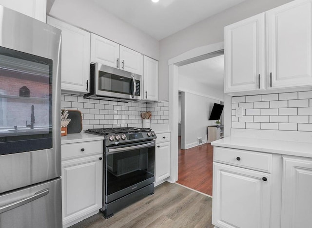 kitchen with light wood-type flooring, white cabinetry, appliances with stainless steel finishes, and light countertops