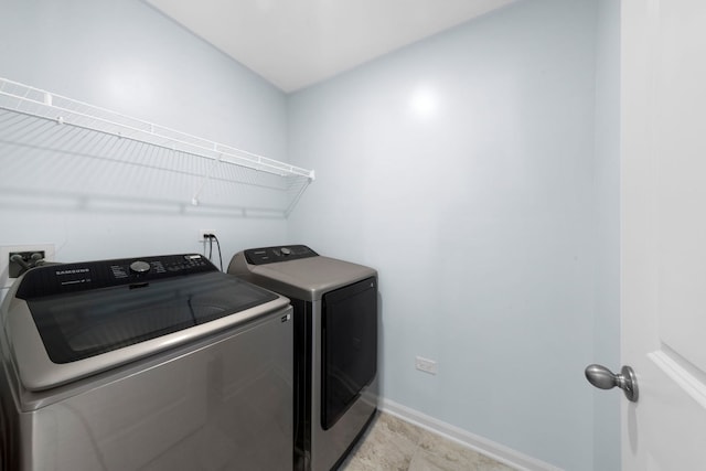 clothes washing area featuring laundry area, baseboards, and washer and clothes dryer