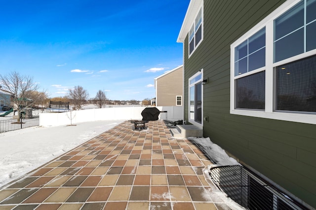 snow covered patio featuring entry steps, a trampoline, and a fenced backyard