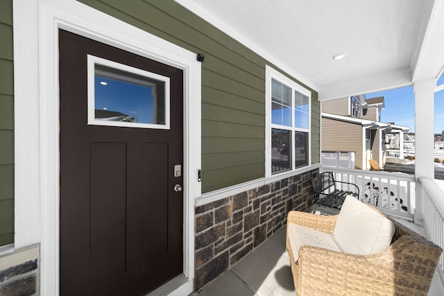 doorway to property featuring stone siding and a porch