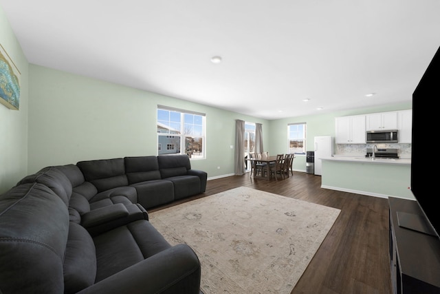 living area featuring dark wood finished floors, a healthy amount of sunlight, and baseboards