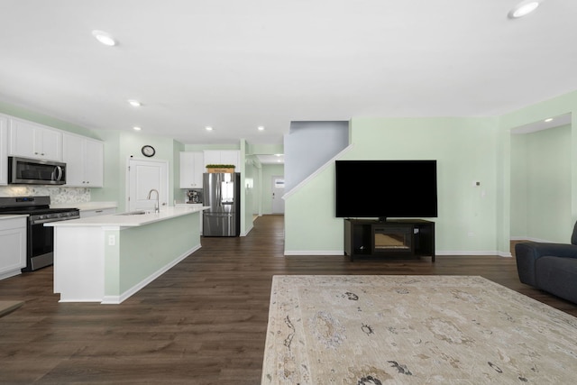 kitchen with a sink, stainless steel appliances, open floor plan, and white cabinetry