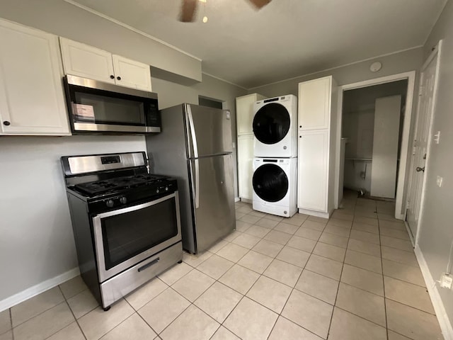 kitchen with light tile patterned floors, appliances with stainless steel finishes, white cabinets, and stacked washing maching and dryer