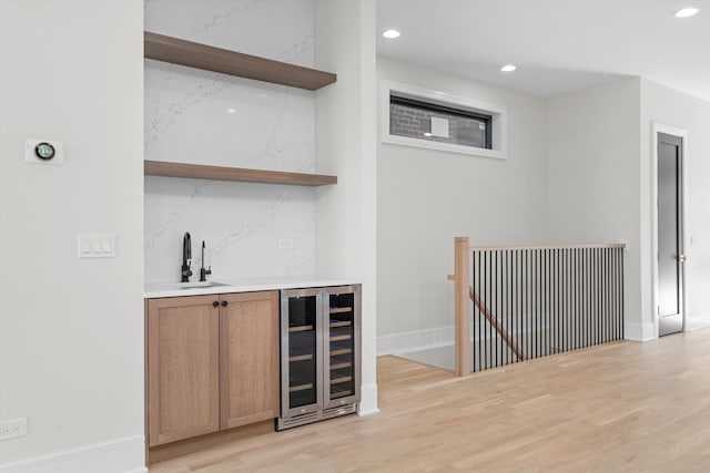 bar featuring light wood-type flooring, a sink, recessed lighting, wine cooler, and indoor wet bar