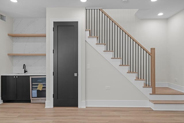 interior space featuring wood finished floors, wine cooler, wet bar, and recessed lighting