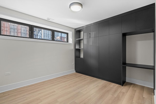 unfurnished bedroom with a closet, visible vents, light wood-style flooring, and baseboards