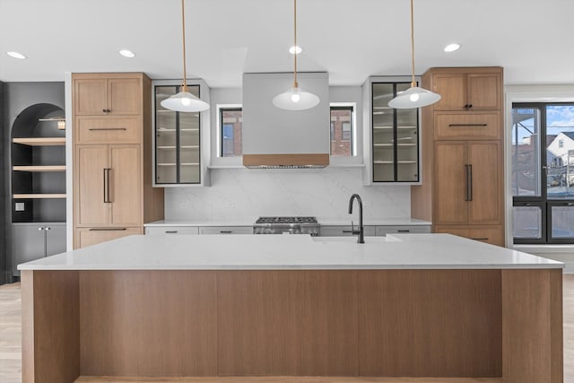 kitchen featuring a large island, a sink, backsplash, and range