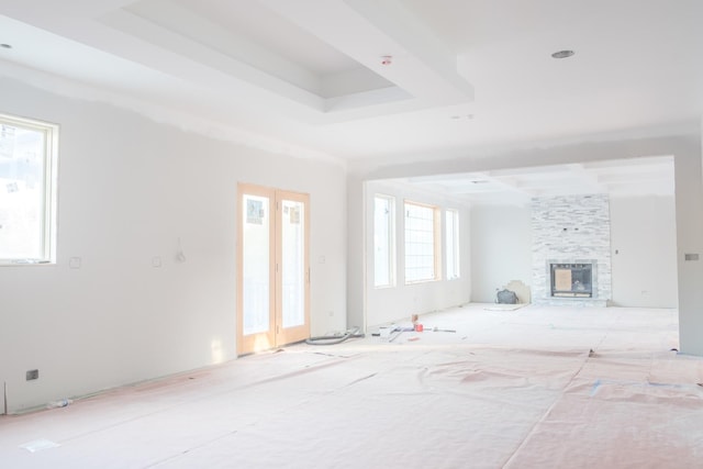 unfurnished living room with a stone fireplace and a tray ceiling