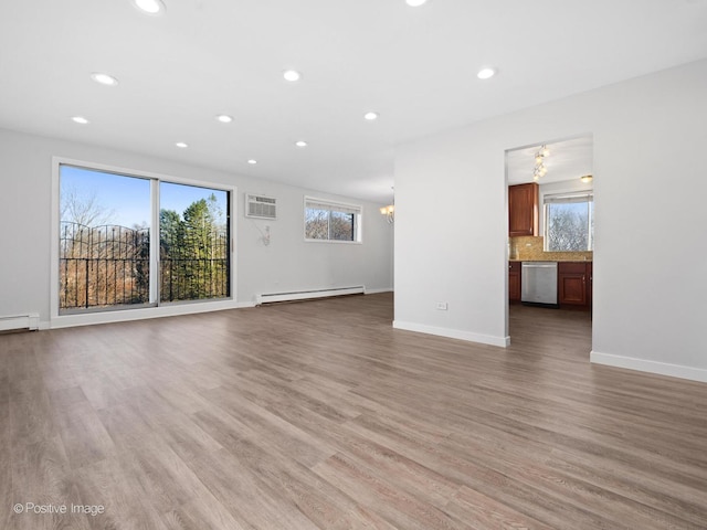 unfurnished living room with a baseboard radiator, baseboards, an inviting chandelier, and light wood finished floors