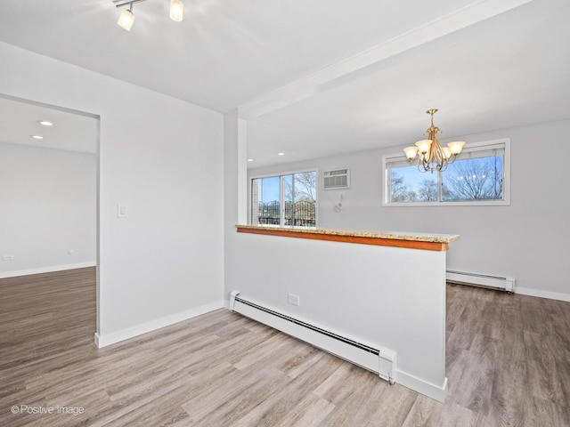 empty room featuring a notable chandelier, baseboard heating, and wood finished floors