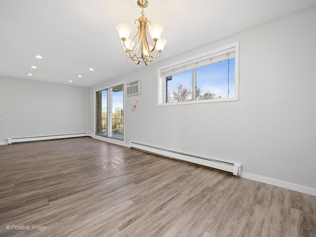 empty room with a notable chandelier, wood finished floors, and a baseboard radiator