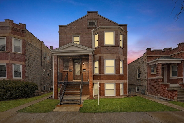 view of front facade featuring brick siding and a lawn