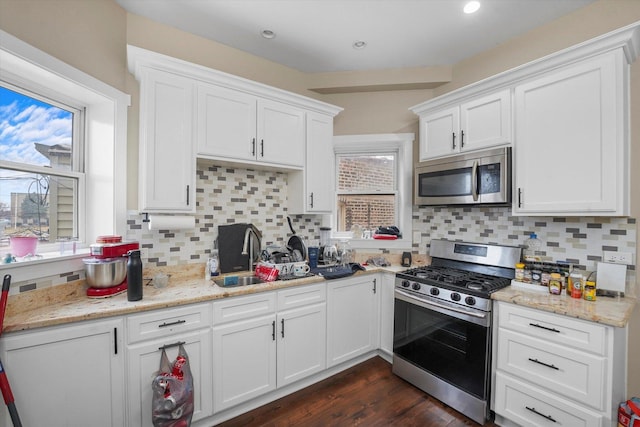 kitchen with a sink, a wealth of natural light, white cabinetry, and stainless steel appliances