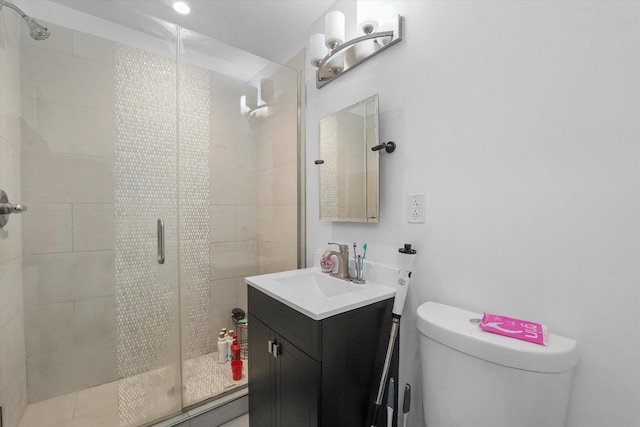 bathroom featuring vanity, a shower stall, and toilet