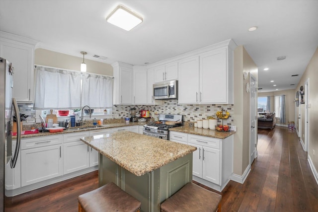 kitchen with a sink, a kitchen island, appliances with stainless steel finishes, and white cabinets