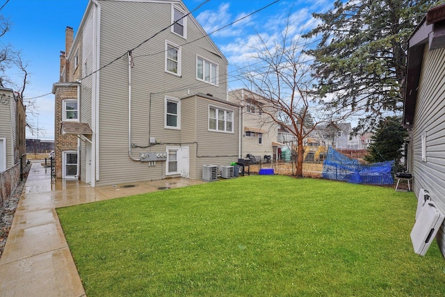 rear view of property with central air condition unit, a lawn, a patio, and fence