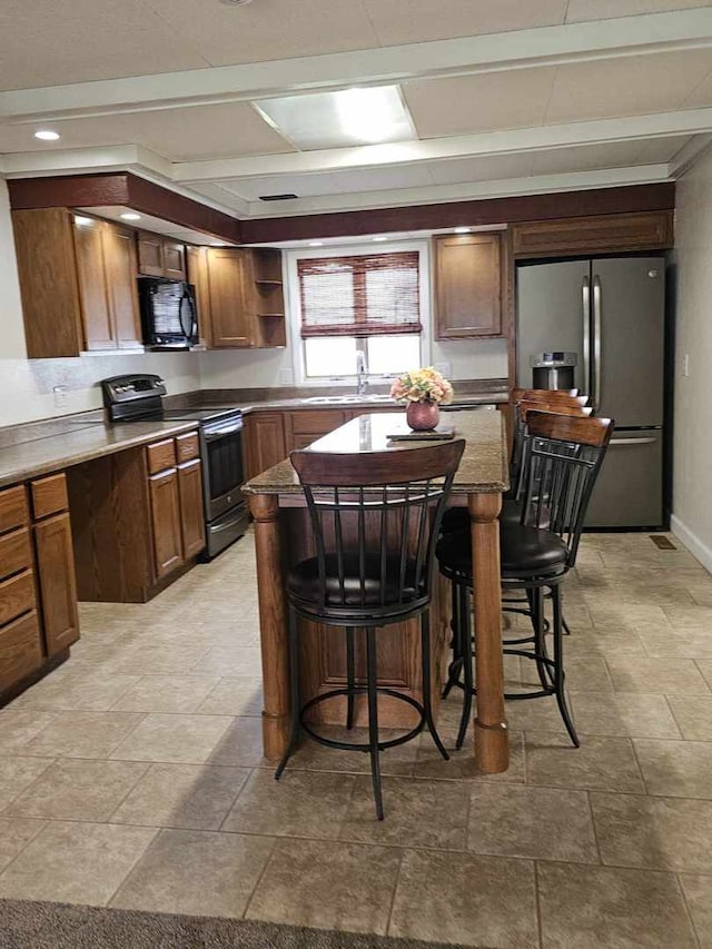 400 S 2nd St, Wapella, IL 61777 - kitchen with appliances with stainless steel finishes, a sink, light stone finish flooring, and a kitchen breakfast bar