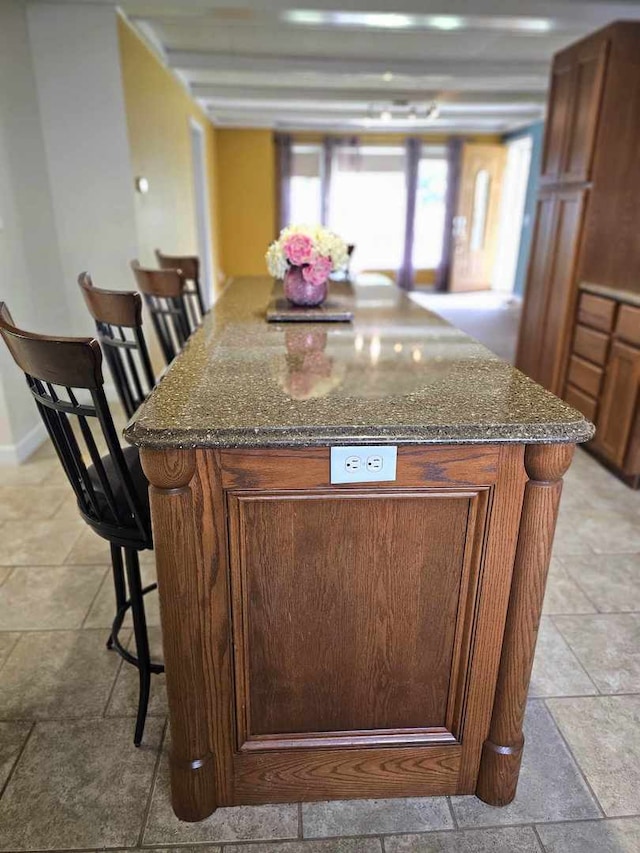 400 S 2nd St, Wapella, IL 61777 - kitchen featuring a breakfast bar, dark stone countertops, brown cabinetry, and a center island