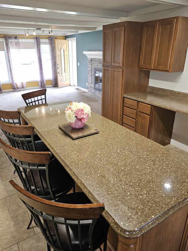 400 S 2nd St, Wapella, IL 61777 - kitchen featuring a breakfast bar, brown cabinets, baseboards, and a fireplace
