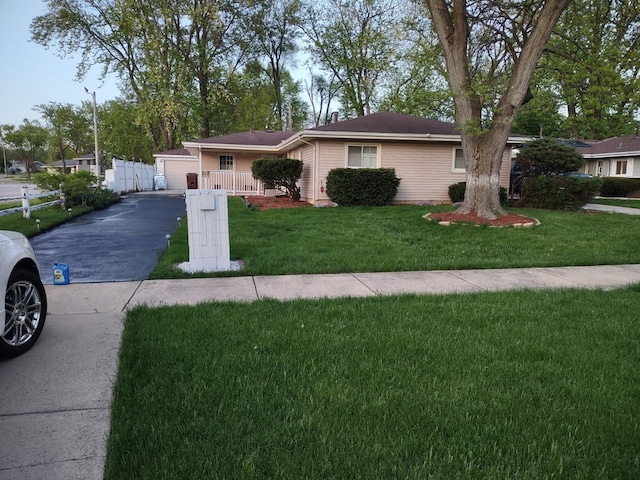 single story home featuring a front lawn, a garage, and fence