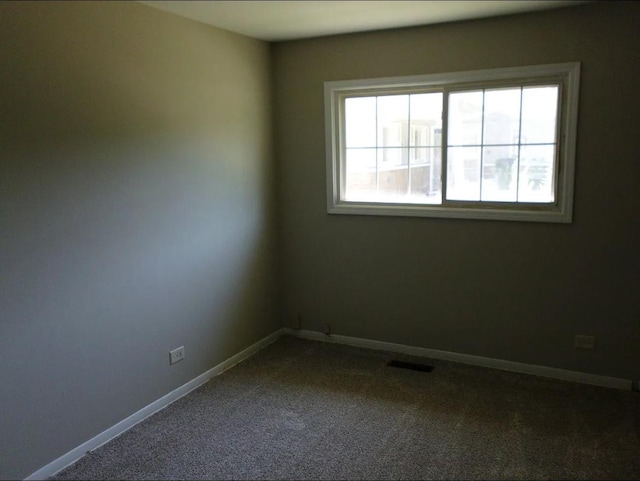 empty room featuring visible vents, baseboards, and dark colored carpet