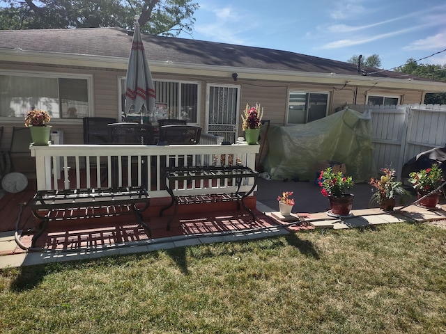 rear view of house with a lawn, roof with shingles, and fence