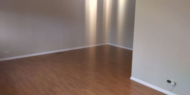 spare room with baseboards and wood finished floors