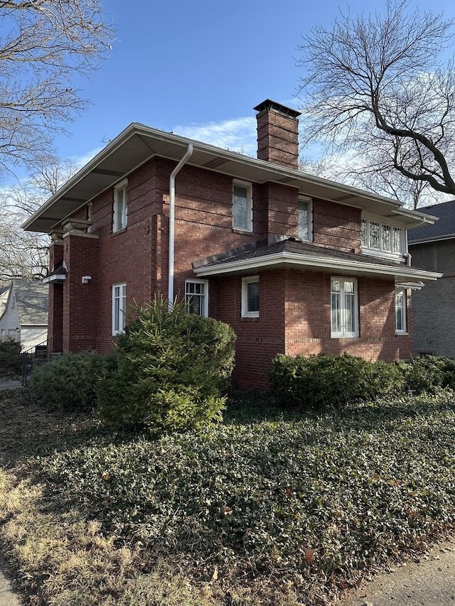 view of property exterior featuring brick siding and a chimney