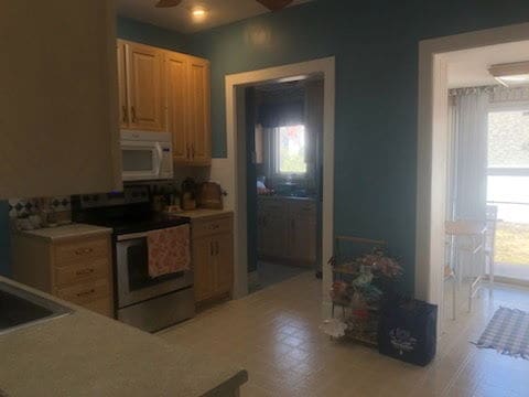 kitchen featuring light countertops, electric range, white microwave, and a sink