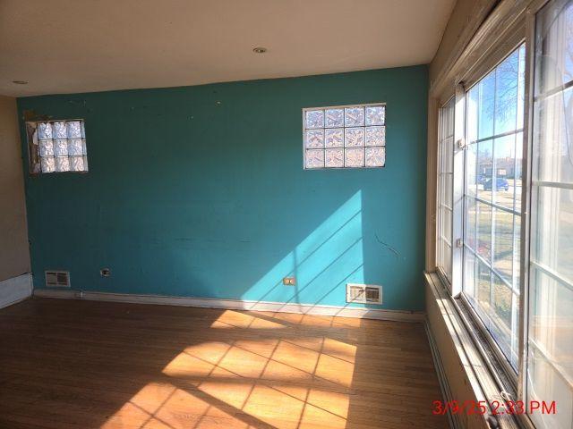 unfurnished room featuring visible vents, baseboards, and wood finished floors