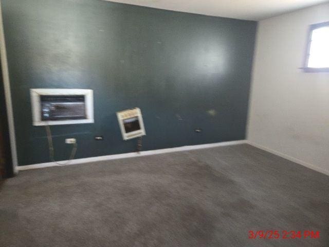 carpeted spare room with heating unit and baseboards