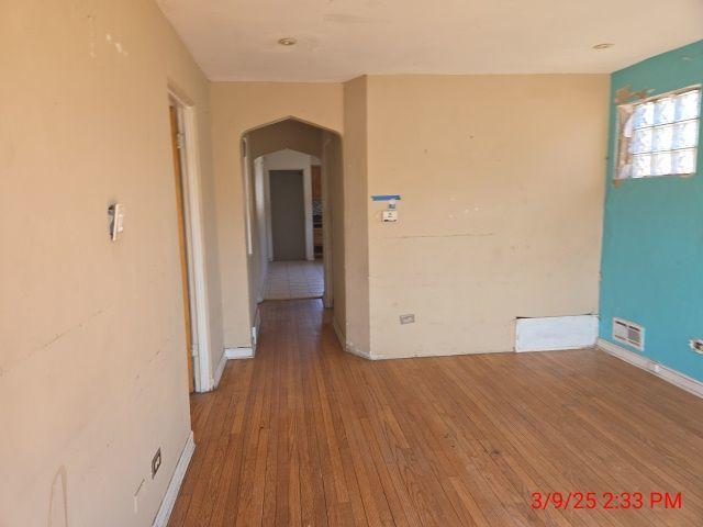 unfurnished room featuring baseboards, arched walkways, visible vents, and wood-type flooring