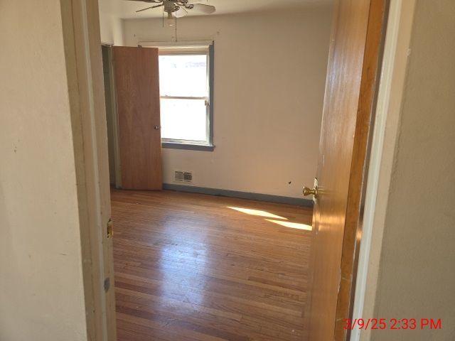 spare room with visible vents, ceiling fan, baseboards, and wood finished floors