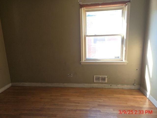 empty room with visible vents, baseboards, and wood finished floors