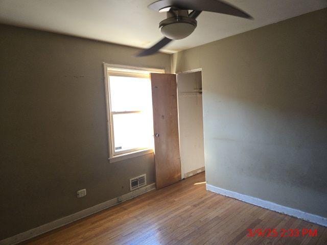 spare room with wood finished floors, a ceiling fan, baseboards, and visible vents